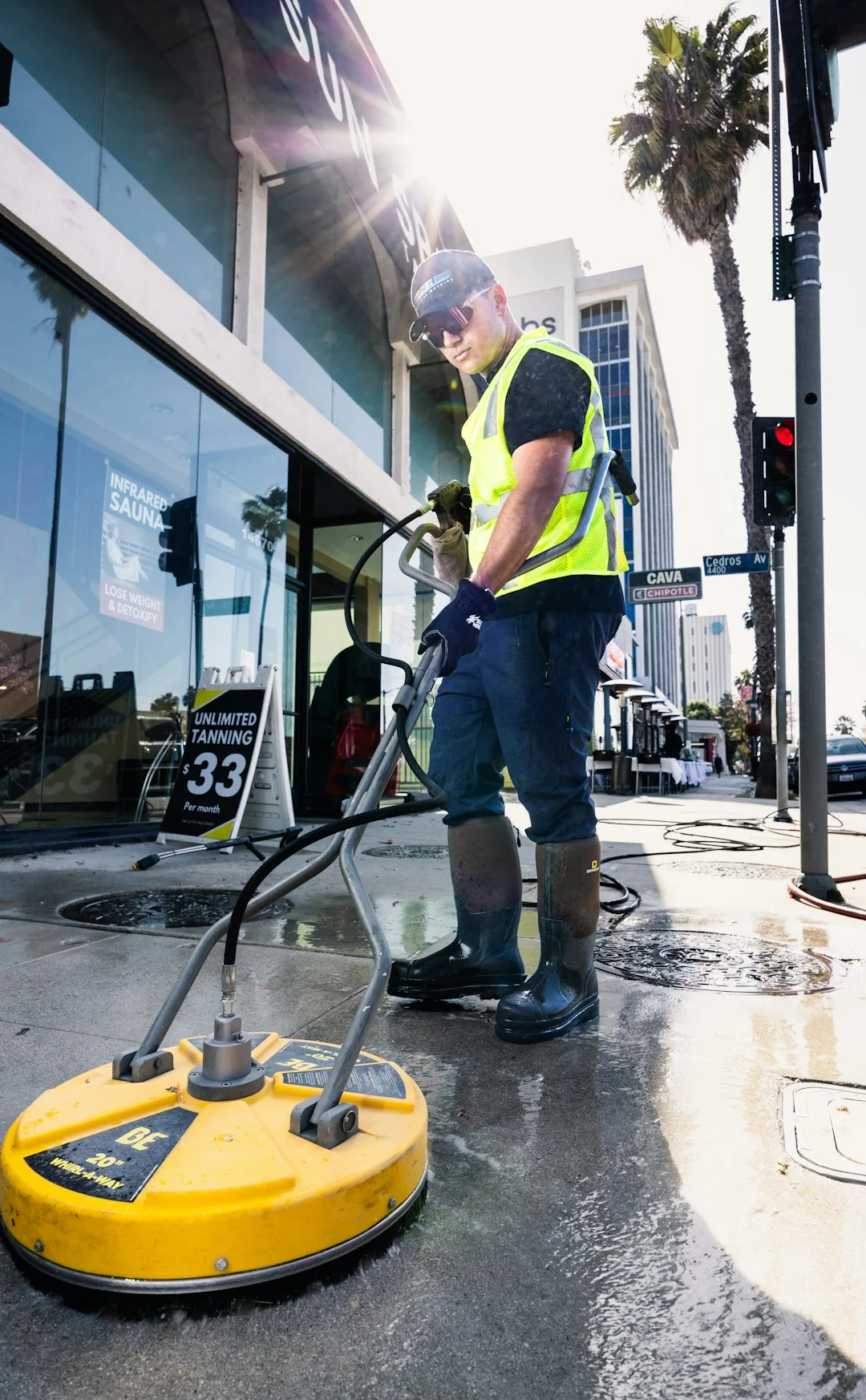 Deux ouvriers nettoient les vitres d'une façade moderne en verre à l'aide d'une plateforme suspendue.